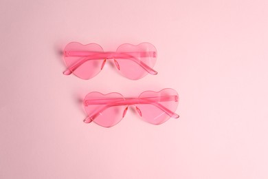 Photo of Stylish heart shaped sunglasses on pink background, top view