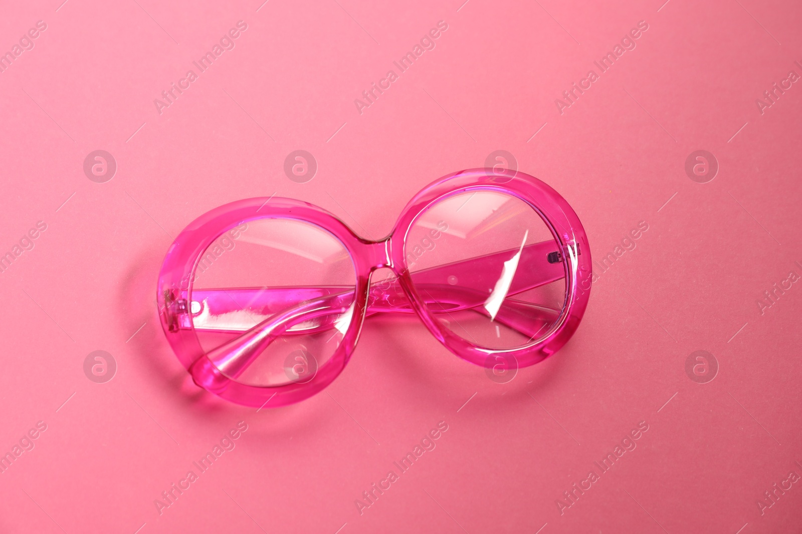 Photo of Stylish bright glasses on pink background, top view