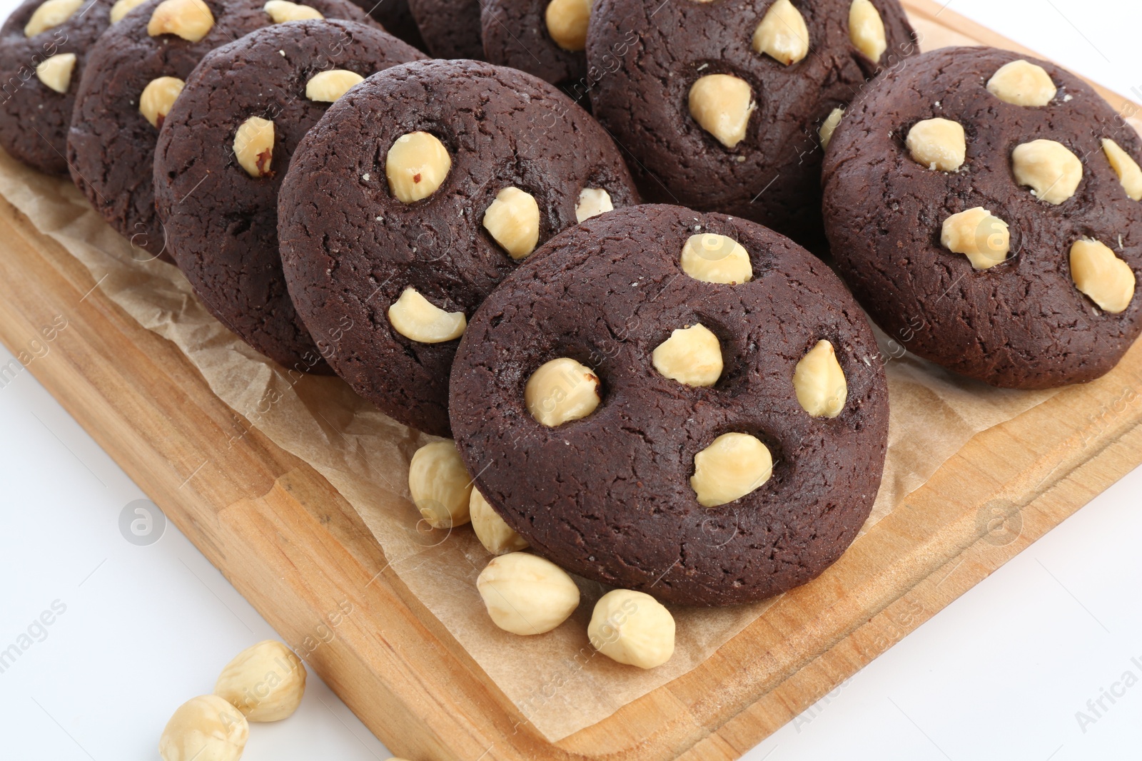 Photo of Tasty chocolate cookies with hazelnuts on white table, closeup