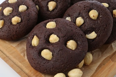 Photo of Tasty chocolate cookies with hazelnuts on white table, closeup