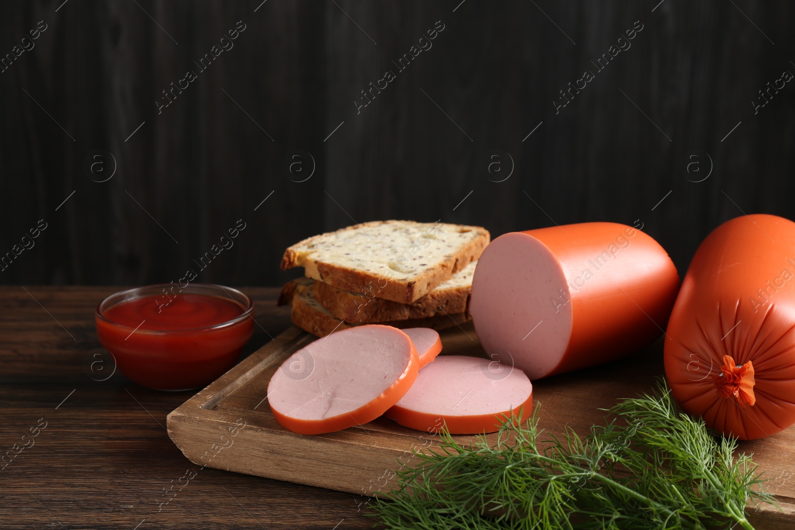 Photo of Tasty boiled sausages, ketchup, dill and bread on wooden table