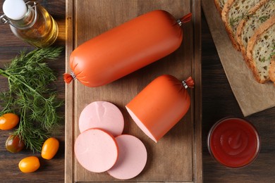 Photo of Tasty boiled sausages, ketchup, tomatoes, dill and bread on wooden table, top view