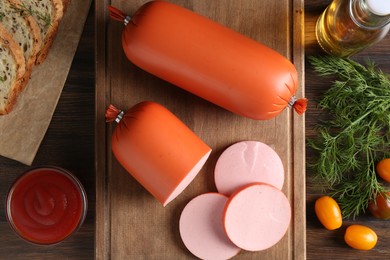 Photo of Tasty boiled sausages, ketchup, tomatoes, dill and bread on wooden table, top view