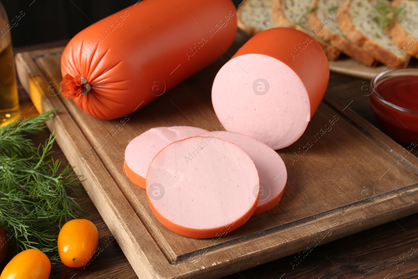 Photo of Tasty boiled sausages, ketchup, tomatoes, dill and bread on wooden table, closeup