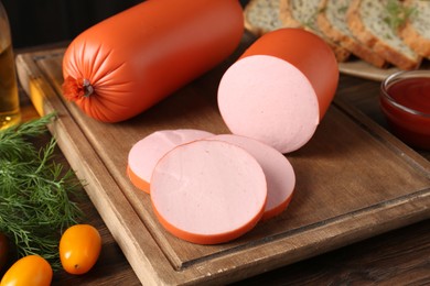 Photo of Tasty boiled sausages, ketchup, tomatoes, dill and bread on wooden table, closeup