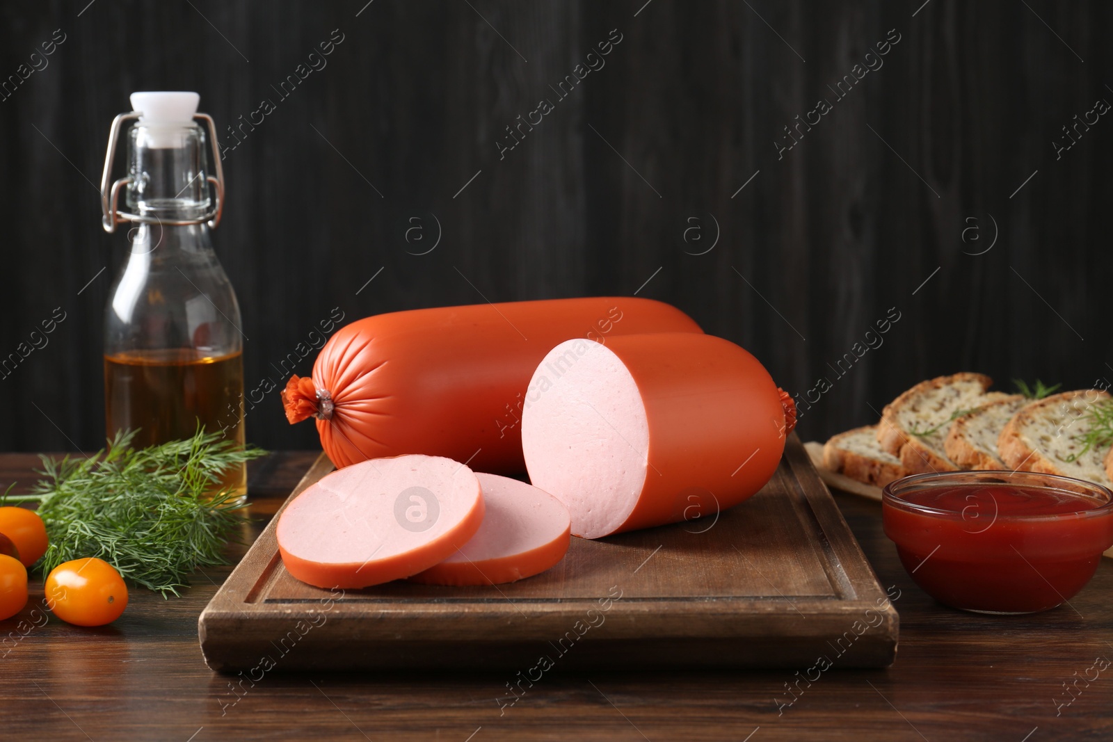 Photo of Tasty boiled sausages, ketchup, tomatoes, dill, oil and bread on wooden table