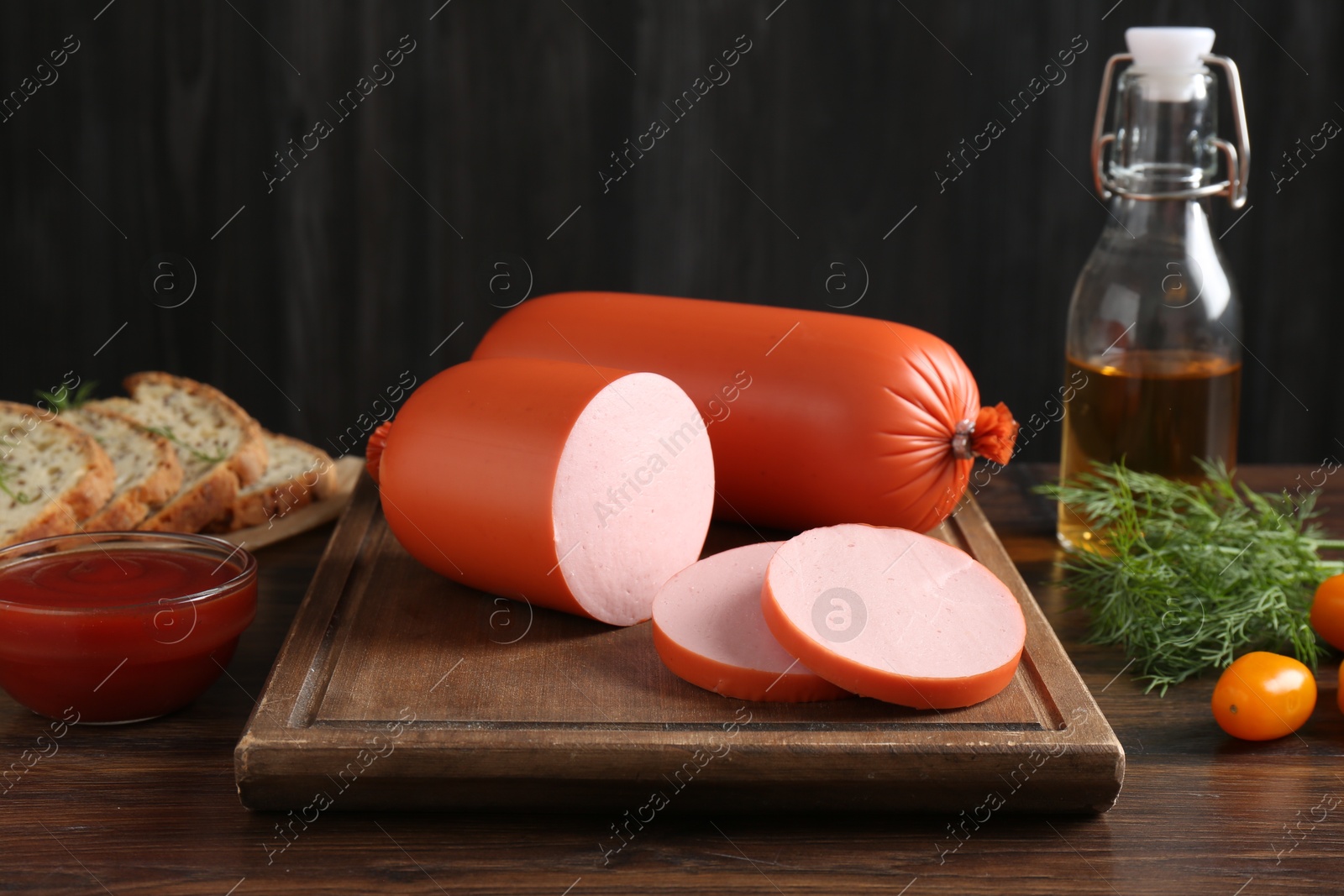 Photo of Tasty boiled sausages, ketchup, dill, oil and bread on wooden table