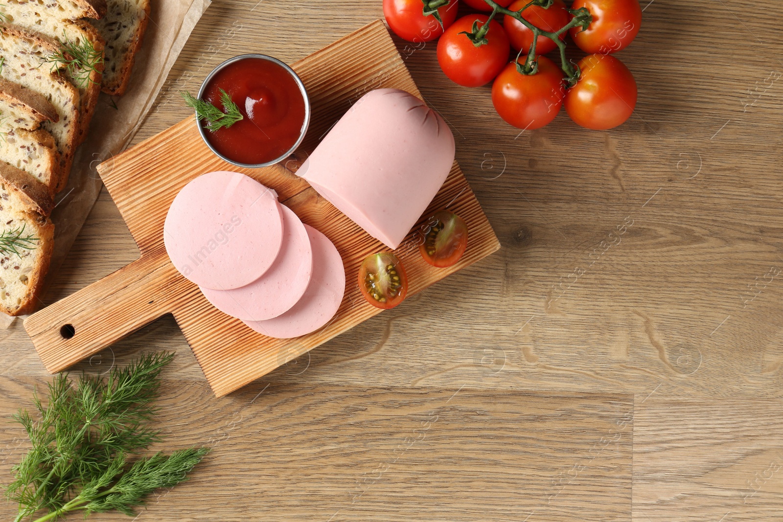 Photo of Tasty boiled sausage, ketchup, tomatoes, dill and bread on wooden table, top view. Space for text