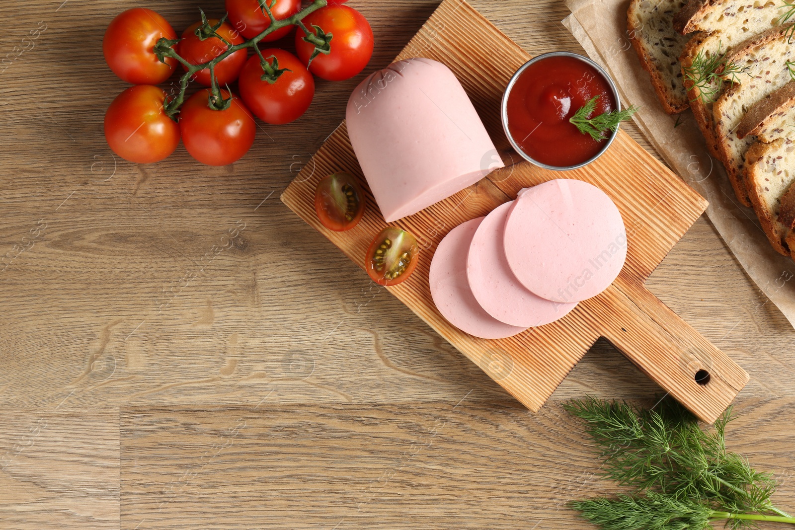 Photo of Tasty boiled sausage, ketchup, tomatoes, dill and bread on wooden table, top view. Space for text