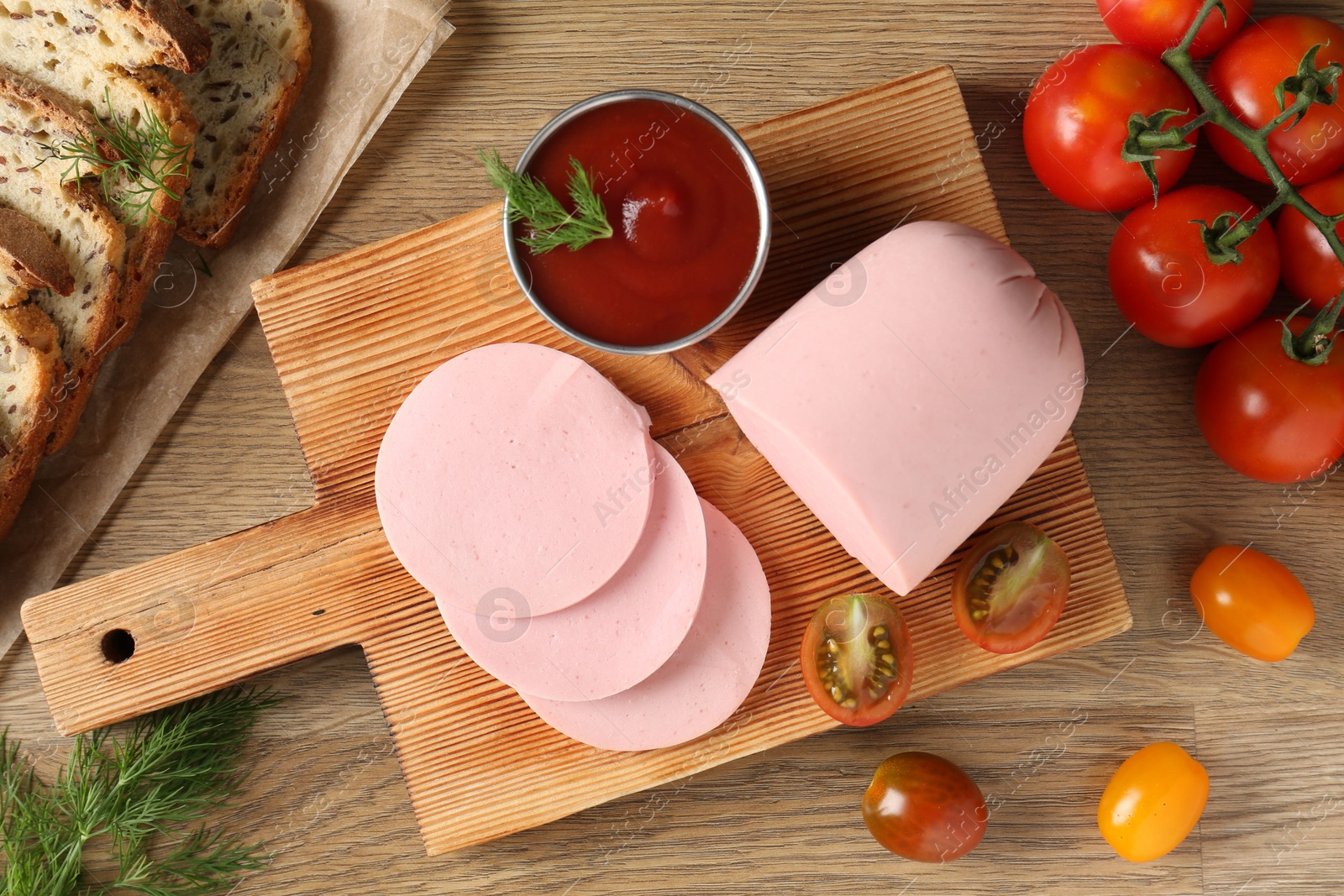 Photo of Tasty boiled sausage, ketchup, tomatoes, dill and bread on wooden table, top view