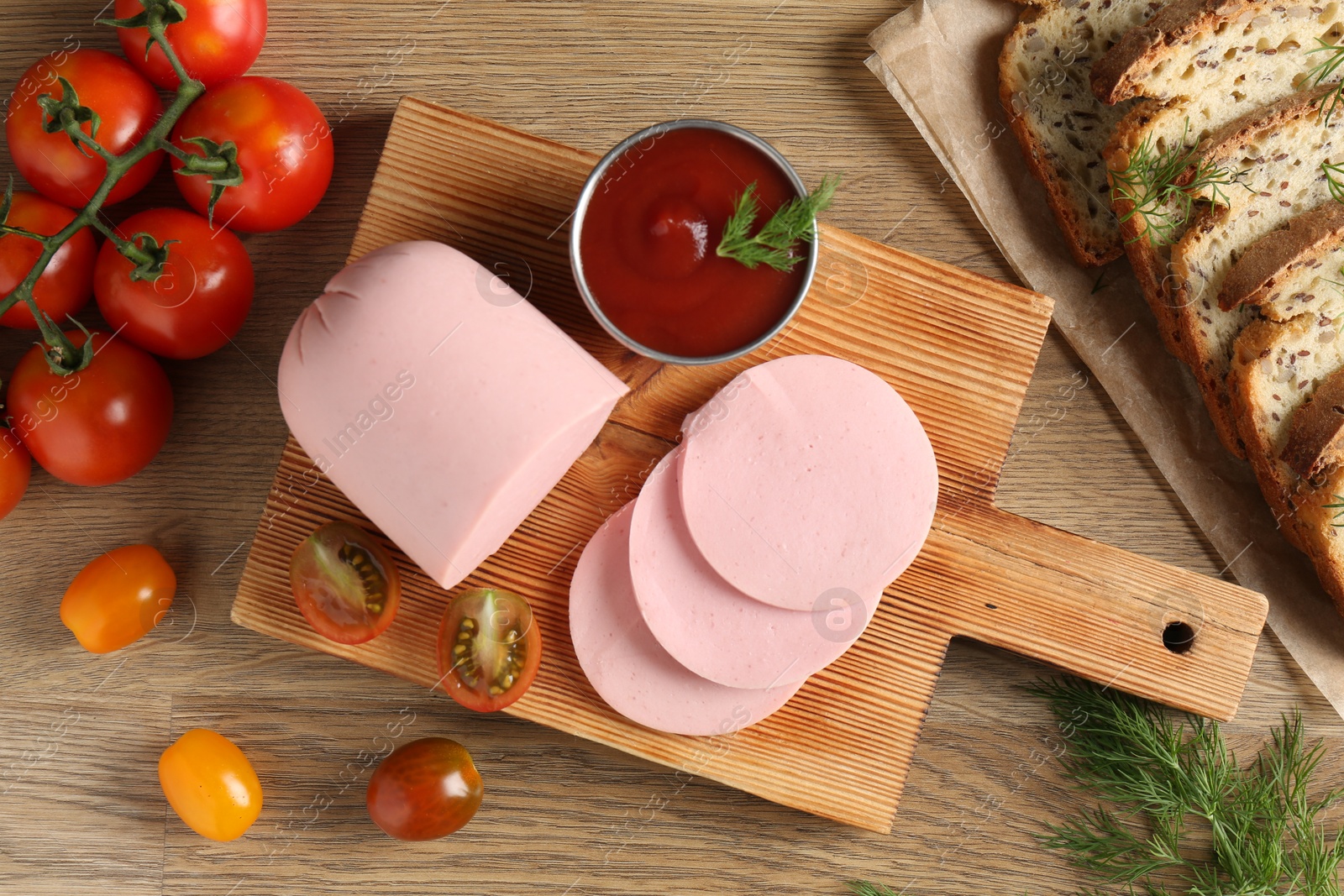 Photo of Tasty boiled sausage, ketchup, tomatoes, dill and bread on wooden table, top view