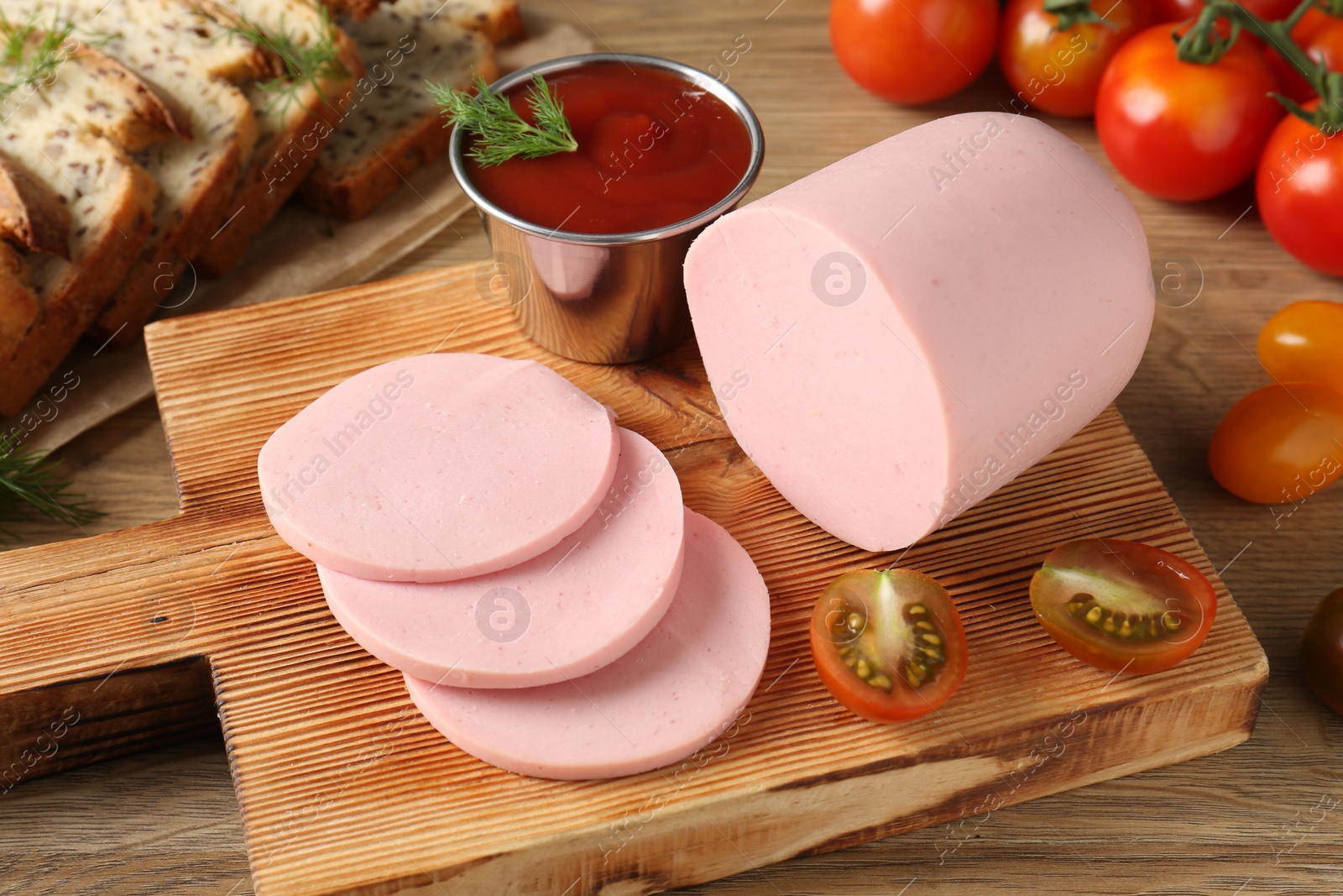 Photo of Tasty boiled sausage, ketchup, tomatoes, dill and bread on wooden table, closeup