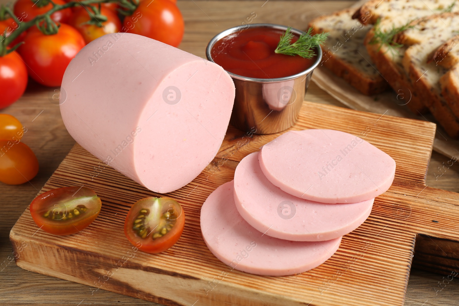 Photo of Tasty boiled sausage, ketchup, tomatoes, dill and bread on wooden table, closeup