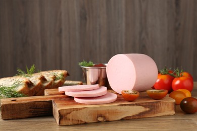 Photo of Tasty boiled sausage, ketchup, tomatoes, dill and bread on wooden table