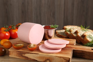 Photo of Tasty boiled sausage, ketchup, tomatoes, dill and bread on wooden table, closeup