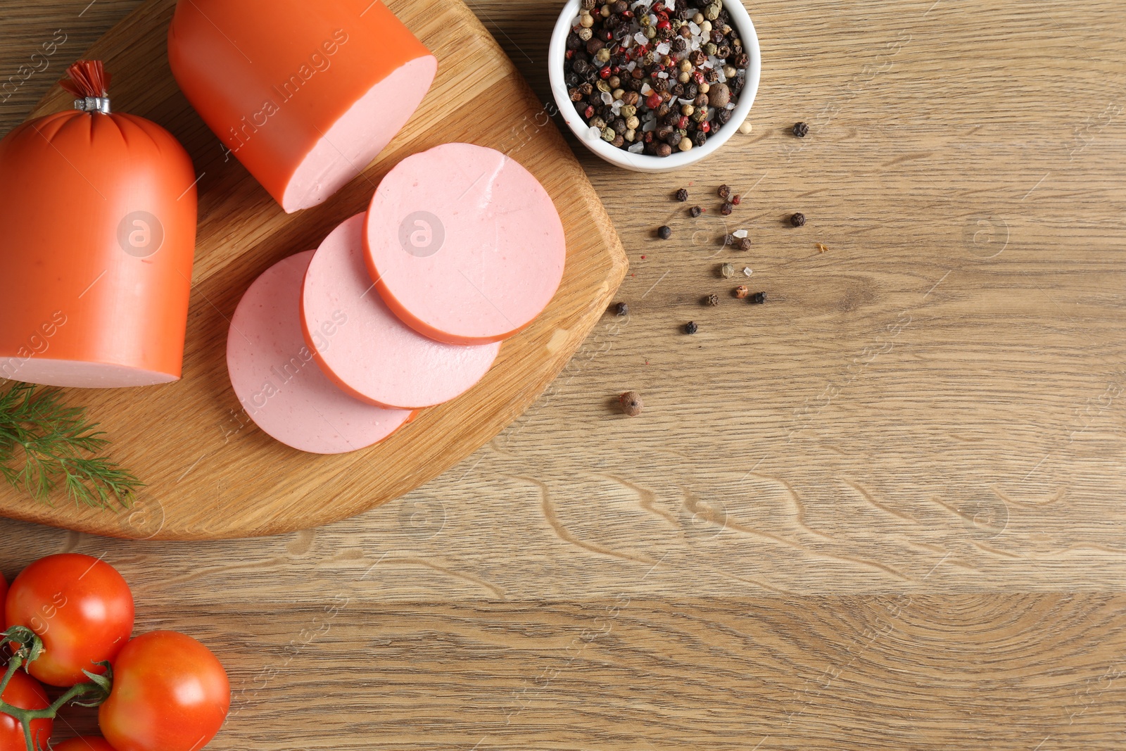 Photo of Tasty boiled sausages, spices and tomatoes on wooden table, top view. Space for text