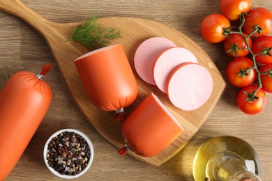 Photo of Tasty boiled sausages, spices and tomatoes on wooden table, top view