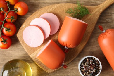 Photo of Tasty boiled sausages, spices and tomatoes on wooden table, top view