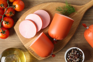 Photo of Tasty boiled sausages, spices and tomatoes on wooden table, top view