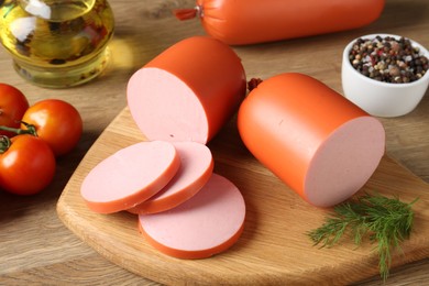 Photo of Tasty boiled sausages, spices and tomatoes on wooden table, closeup