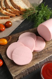 Photo of Tasty boiled sausage, tomatoes, dill, bread and ketchup on black table, closeup