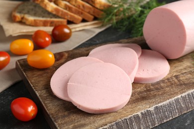 Photo of Tasty boiled sausage, tomatoes, dill and bread on black table, closeup