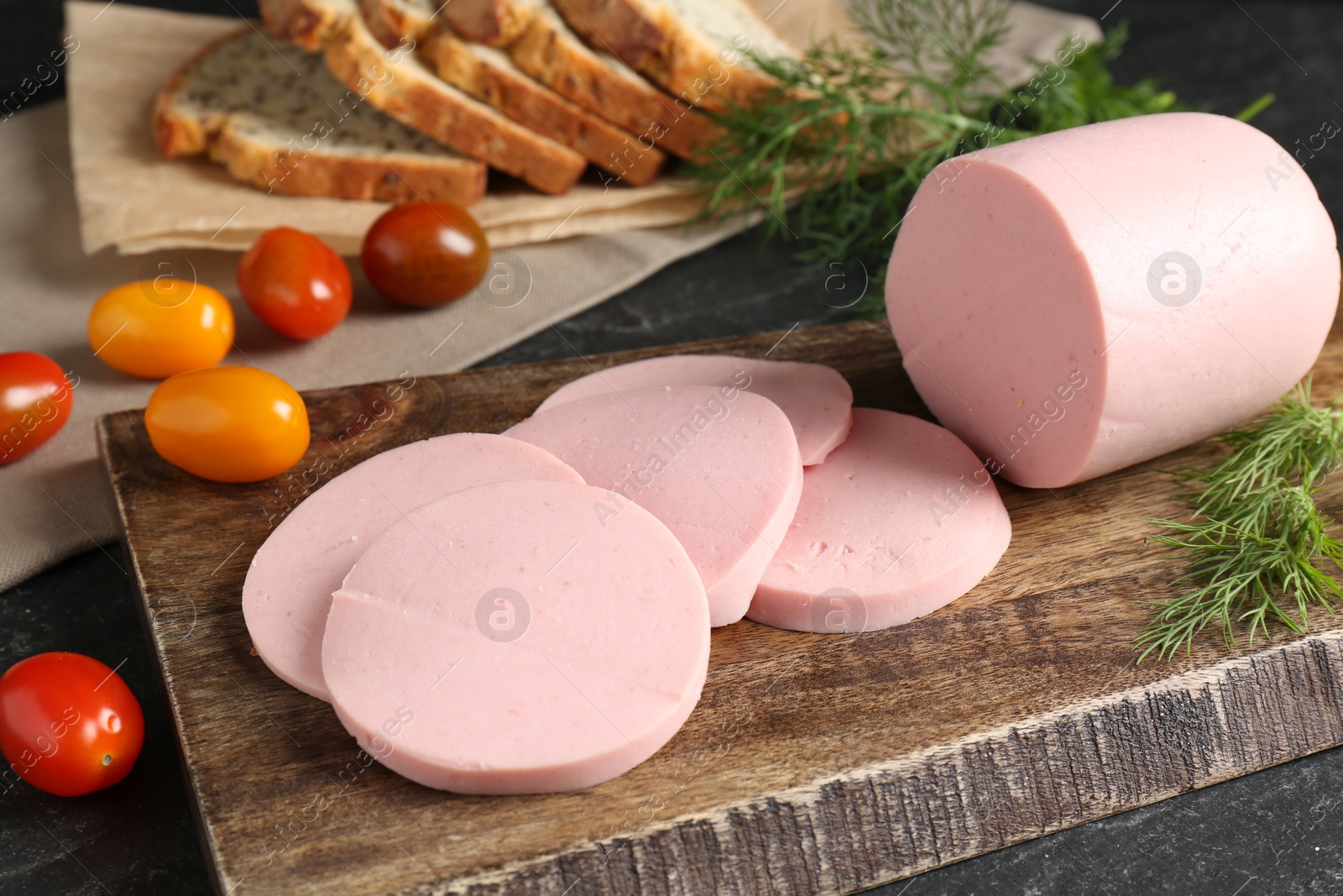 Photo of Tasty boiled sausage, tomatoes, dill and bread on black table, closeup