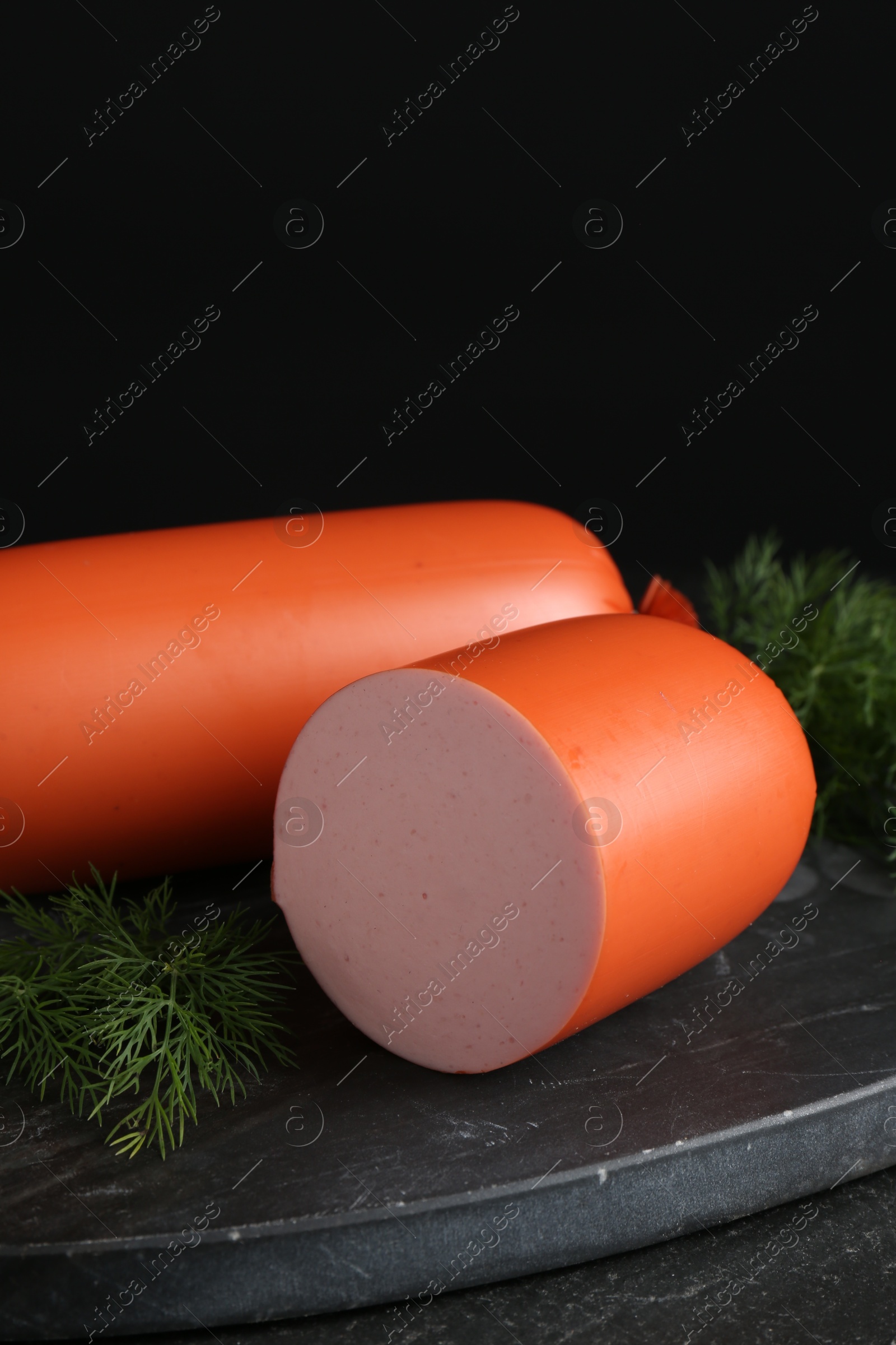 Photo of Tasty boiled sausages and dill on black table, closeup