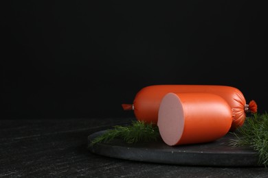 Photo of Tasty boiled sausages and dill on black table, space for text