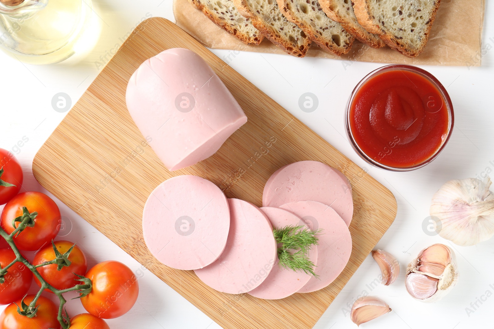 Photo of Tasty boiled sausage, spices, tomatoes, ketchup and bread on white table, top view