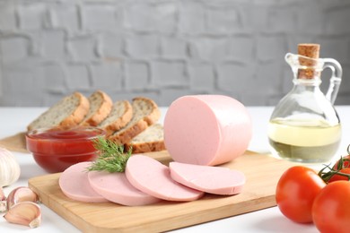 Photo of Tasty boiled sausage, spices, tomatoes, ketchup and bread on white table, closeup