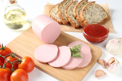 Photo of Tasty boiled sausage, spices, tomatoes, ketchup and bread on white table