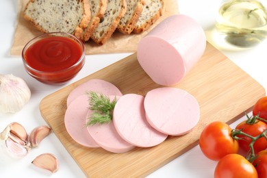 Photo of Tasty boiled sausage, spices, tomatoes, ketchup and bread on white table