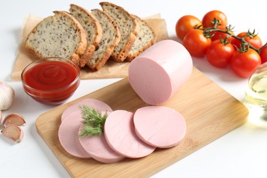 Photo of Tasty boiled sausage, spices, tomatoes, ketchup and bread on white table