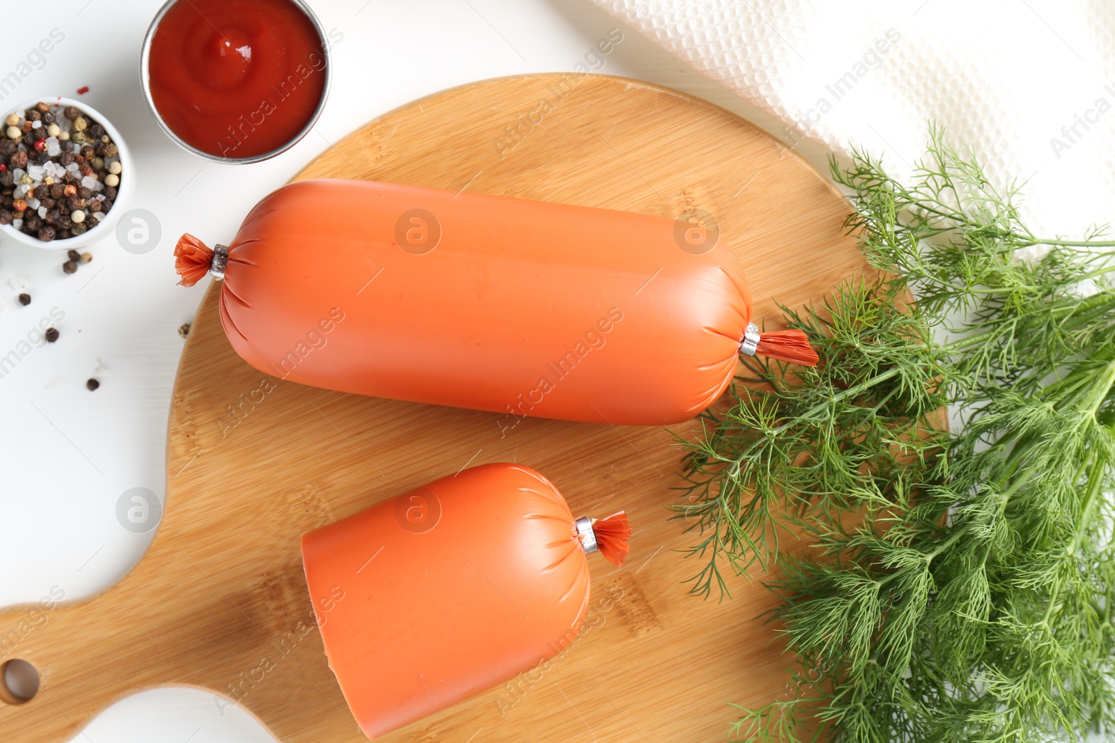 Photo of Tasty boiled sausages, ketchup and spices on white table, top view