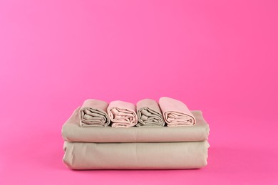 Photo of Stack of clean bed sheets on pink background