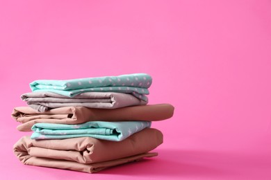 Photo of Stack of clean bed sheets on pink background. Space for text