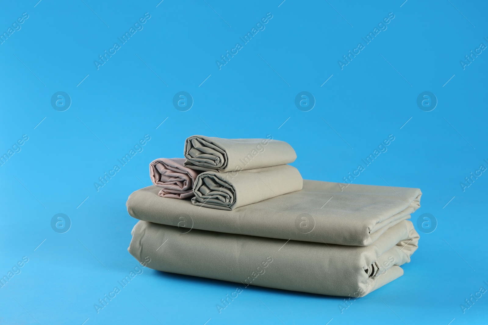 Photo of Stack of clean bed sheets on blue background