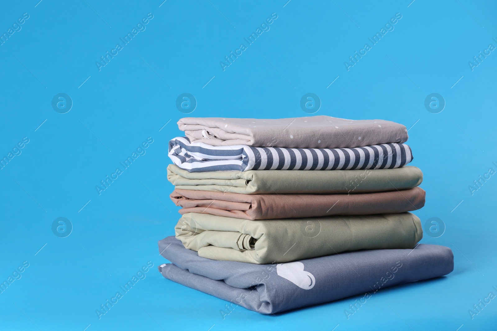 Photo of Stack of clean bed sheets on blue background