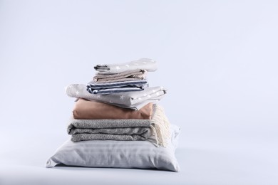 Photo of Stack of clean bed sheets and pillow on white background. Space for text