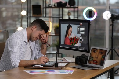 Photo of Tired retoucher at table with modern computer in office