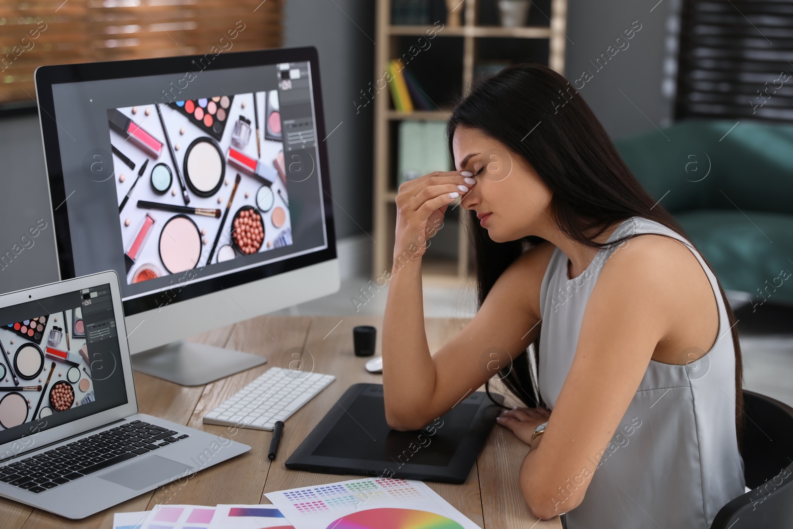 Photo of Tired retoucher at workplace with computer and laptop in office