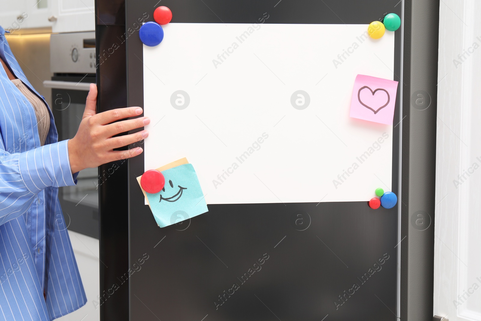 Photo of Woman opening refrigerator with blank magnetic board and notes in kitchen, closeup