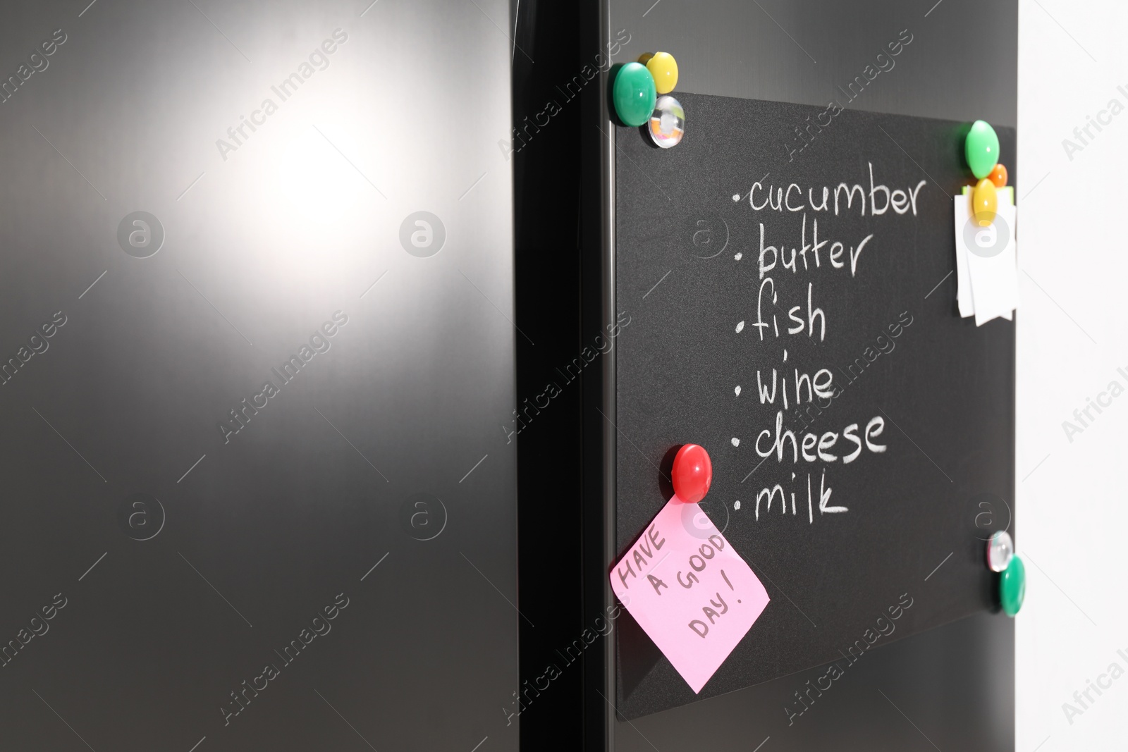 Photo of Magnetic board with shopping list and notes on refrigerator in kitchen