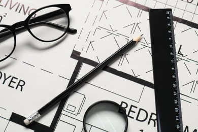 Ruler, glasses, magnifying glass and pencil on different architectural drawings, top view