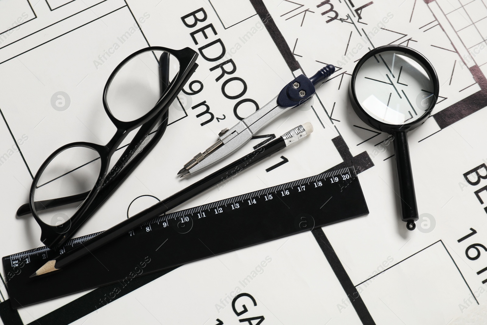 Photo of Ruler, glasses, dividers, magnifying glass and pencil on different architectural drawings, top view