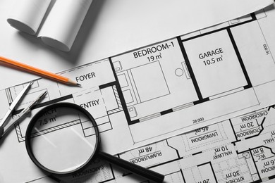 Photo of Pencil, dividers and magnifying glass on different architectural drawings, top view