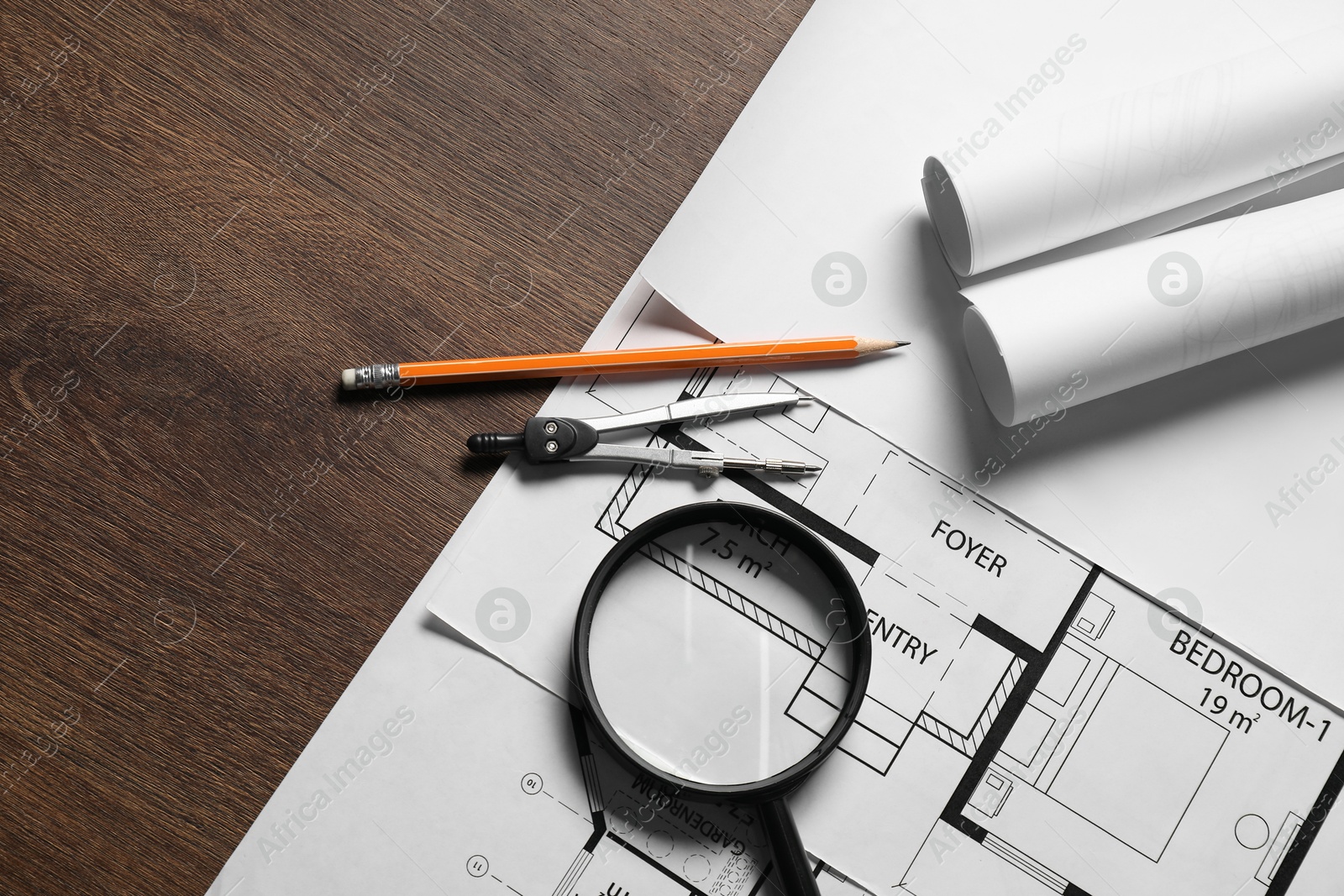 Photo of Different architectural drawings, pencil, magnifying glass and dividers on wooden table, flat lay