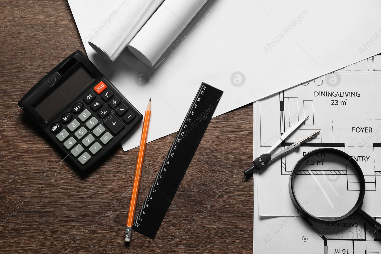 Photo of Different architectural drawings, pencil, magnifying glass, ruler, calculator and dividers on wooden table, flat lay