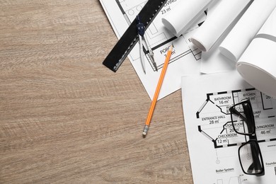 Photo of Different engineering drawings, glasses, ruler, pencil and dividers on wooden table, flat lay. Space for text